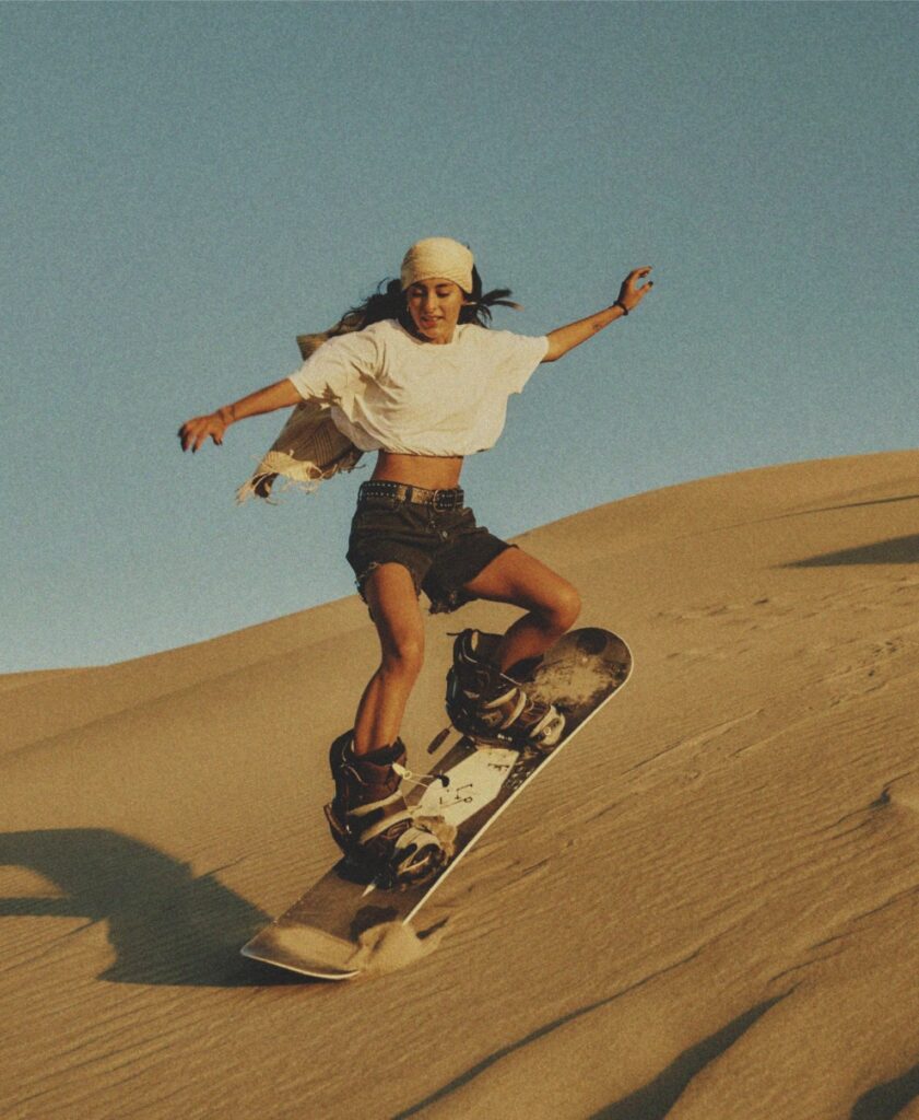 A woman on a board on sand dunes
