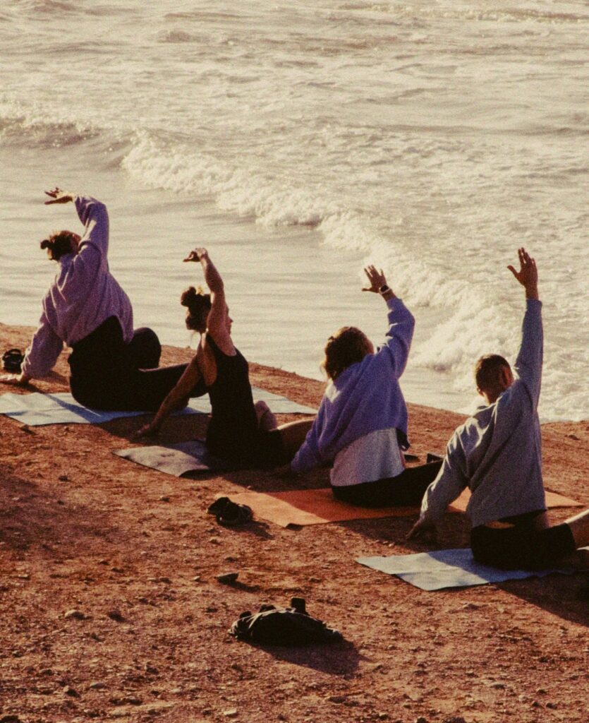 A group of surfers doing yoga on the beach